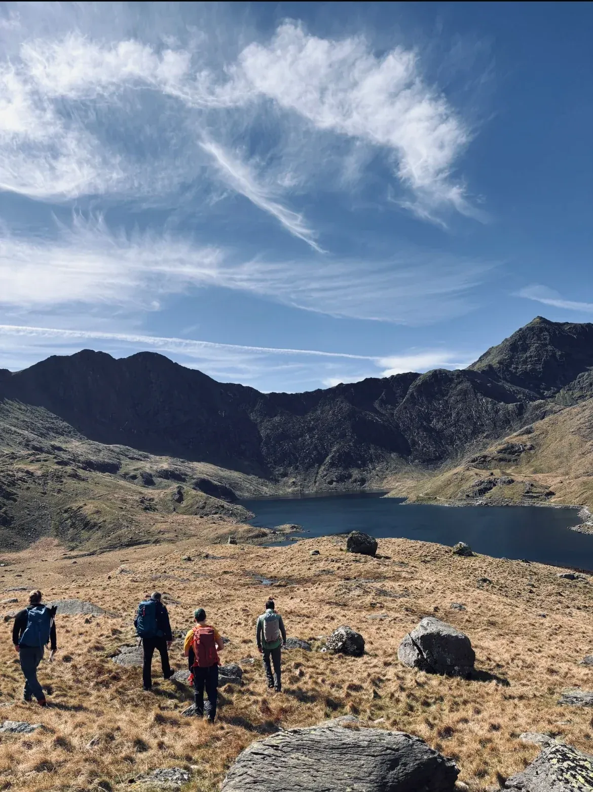 Walkers heading towards a lake below the Snowdon Horseshoe